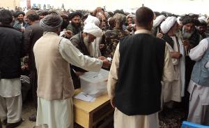 Wähler mit Wahlzettel stehen um eine Wahlurne. Foto: Helmand PRT Lashkar Gah/Flickr