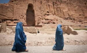 Zwei vollverschleierte Frauen laufen an den Überresten der von den radikalislamischen Taliban im Jahr 2001 zerstörten Buddha-Statuen im Bamiyan-Tal vorbei. | © Sgt. Ken Scar / Flickr / CC BY 2.0