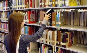 Eine Studentin nimmt in der Bibliothek ein Buch aus dem Regal. | Foto: Joe Crawford/wikipedia