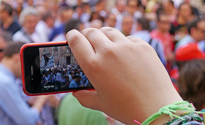 Ein Jugendlicher filmt eine Demonstration auf der Straße. | Foto: Chris Brown/Flickr Ein Jugendlicher filmt eine Demonstration auf der Straße. | Foto: Chris Brown/Flickr