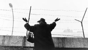 Eine ältere Frau, die mit erhobenen Händen an der Berliner Mauer im Westsektor stand, nachdem sie drei Stunden gewartet hatte, um ihre Freunde und Verwandten in Ostberlin zu sehen. | Foto: wikimedia/gemeinfrei