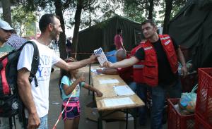 Ein Freiwilliger vom Internationalen Roten Kreuz übergibt im serbischen Preševo einem Flüchtling Milch für dessen Kind, 27.08.2015.