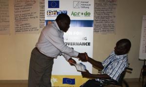 At Masaka Councillors' workshop, training facilitator Prof. Yasin Olum hands over the certificate of attendance to Mr. Bruno Mugumya, the councillor representing people with disabilities in Masaka district council.