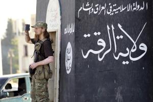 A militant Islamist fighter uses a mobile to film his fellow fighters taking part in a military parade along the streets of Syria's northern Raqqa province June 30, 2014