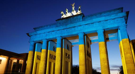 Das Bild zeigt das Brandenburger Tor  in Berlin. Es ist in ukrainischen Nationalfarben beleuchtet.
