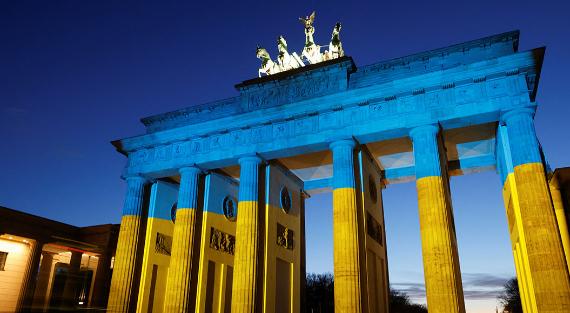 Das Bild zeigt das Brandenburger Tor in Berlin. Es ist in ukrainischen Nationalfarben beleuchtet.