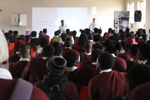 A large number of learners attentively listening to Zola acting as "Thandi" and Pule acting as "Sipho".