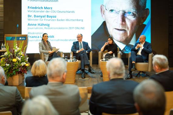 Dr. Danyal Bayaz, Firedrich März und Anne Hähnig sitzen auf einem Podium während einer Diskussion, moderiert von Franca Lehfeldt.