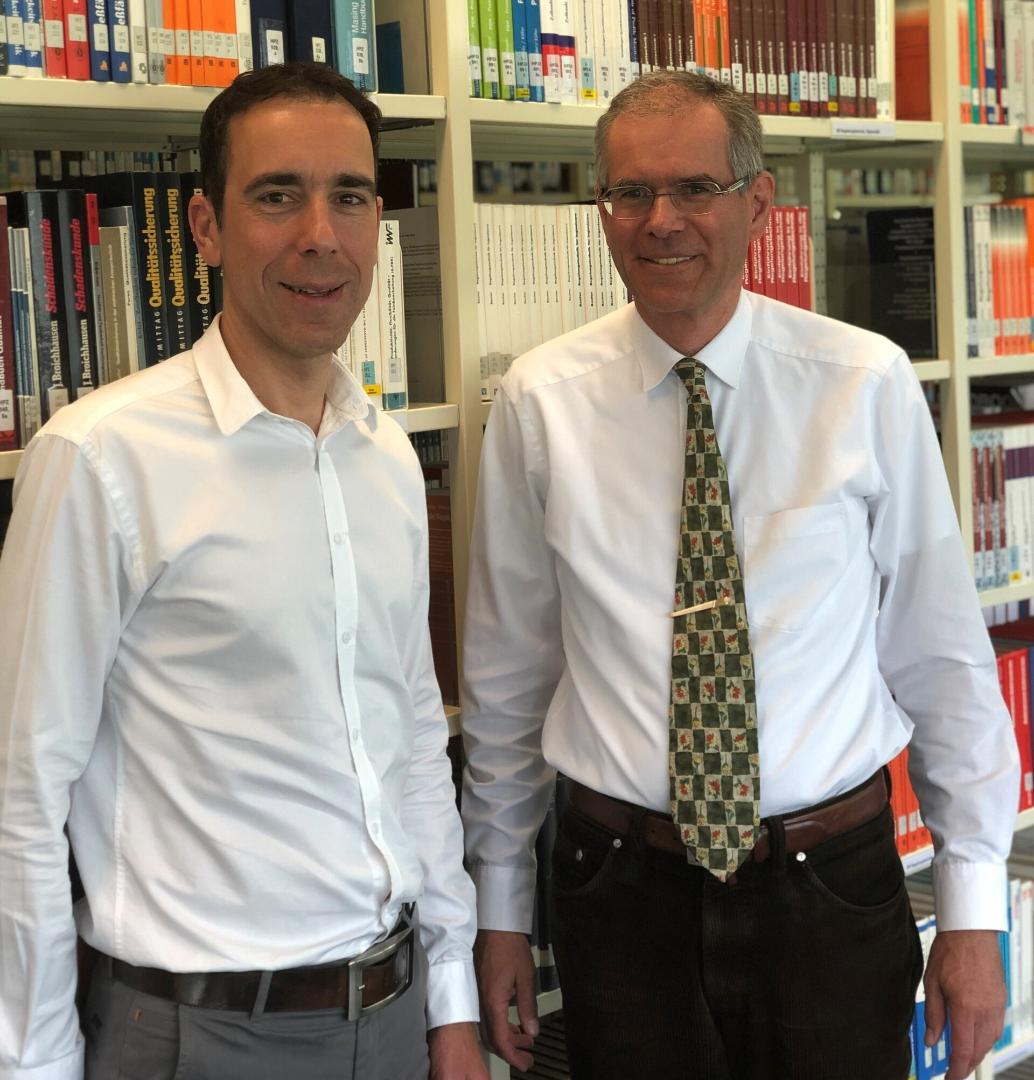 Brunßen und Hilligweg stehen nebeneinander vor einem Bücherregal.