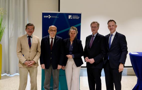 Fünf Personen in formeller Kleidung stehen vor zwei aufgestellten Bannern der Konrad-Adenauer-Stiftung