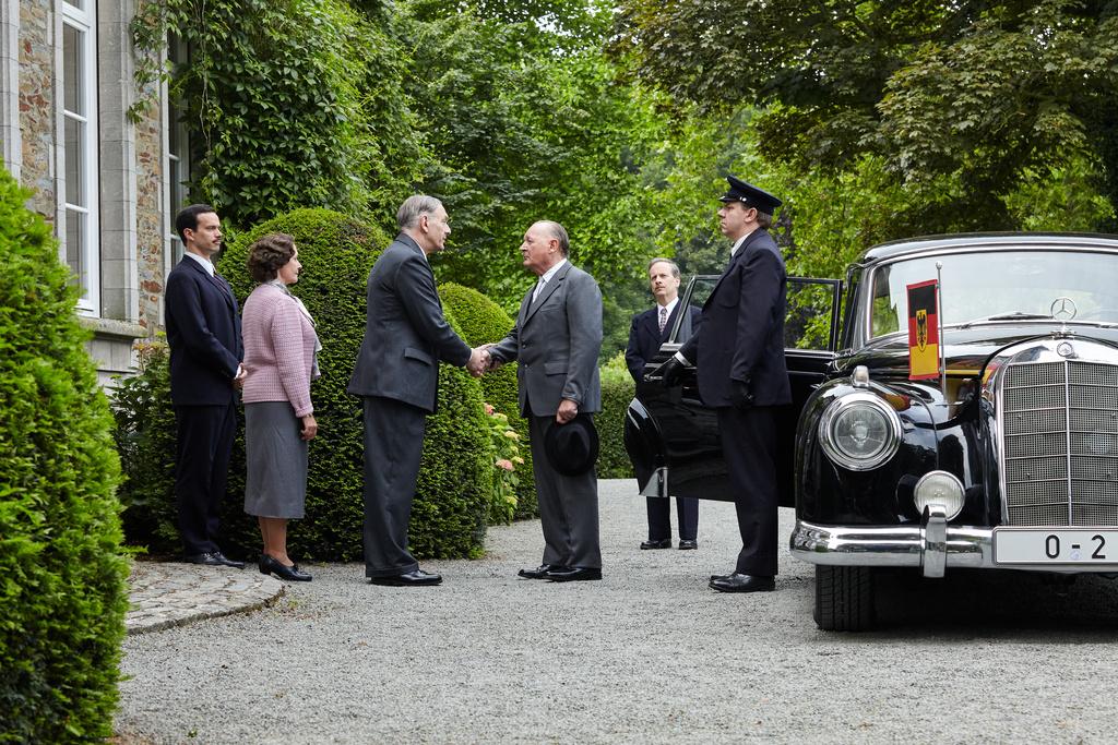14. September 1958: Bundeskanzler Konrad Adenauer (Burghart Klaußner, 3.v.r.) und Ministerpräsident Charles de Gaulle (Jean-Yves Berteloot, 3.v.l.) begegnen sich zum ersten Mal im beschaulichen Colombey-les-Deux-Églises. Nicht nur Ehefrau Yvonne (Hélène Alexandridis, 2.v.l.) und Sohn Philippe (Pierre Lognay, l.) schauen mit Spannung auf das Treffen. Auch Adenauers Berater Günther Bachmann (Fabian Busch, 2.v.r.) und Fahrer Willi Klockner (Ronald Kukulies, r.) haben ihre eigene Meinung zu diesem historischen Moment.