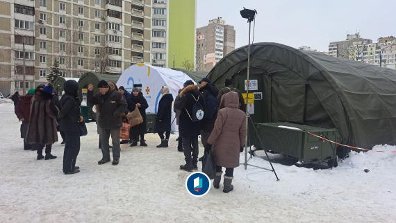 Kyiv im Februar 2026: Im Stadtteil Trojeschtschyna stehen Menschen während eines Luftalarms vor Wärmezelten und warten auf die Nachricht für die Entwarnung.