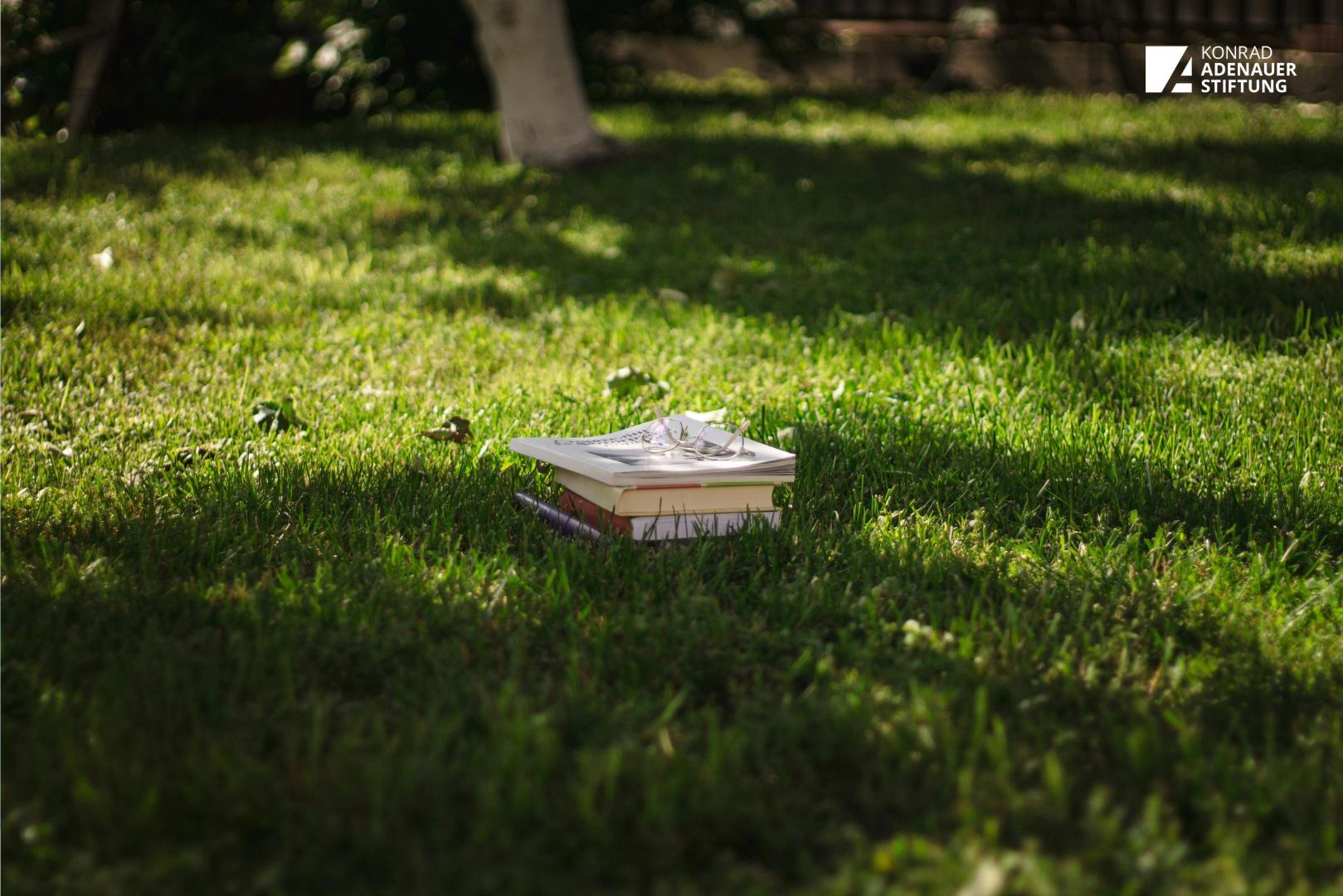 Bücher und Brillen auf saftig grünem Rasen