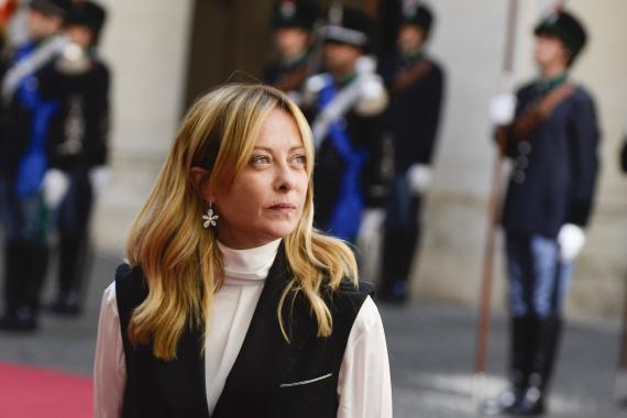 Giorgia Meloni steht vor uniformierten Ehrenwachen bei einer Zeremonie im Freien.