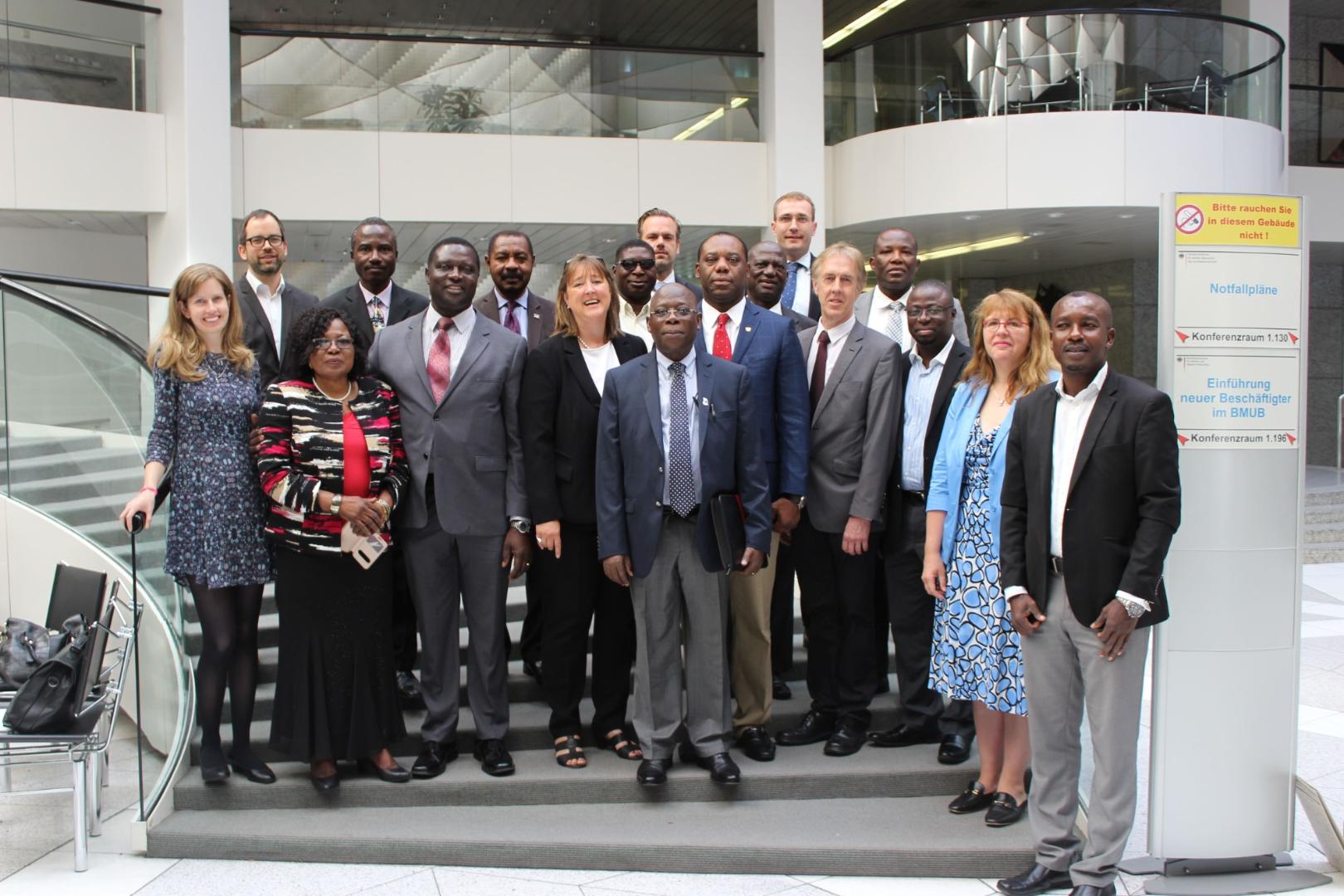 Group photo of an international delegation of women and men in formal attire in the foyer of the German Federal Ministry.