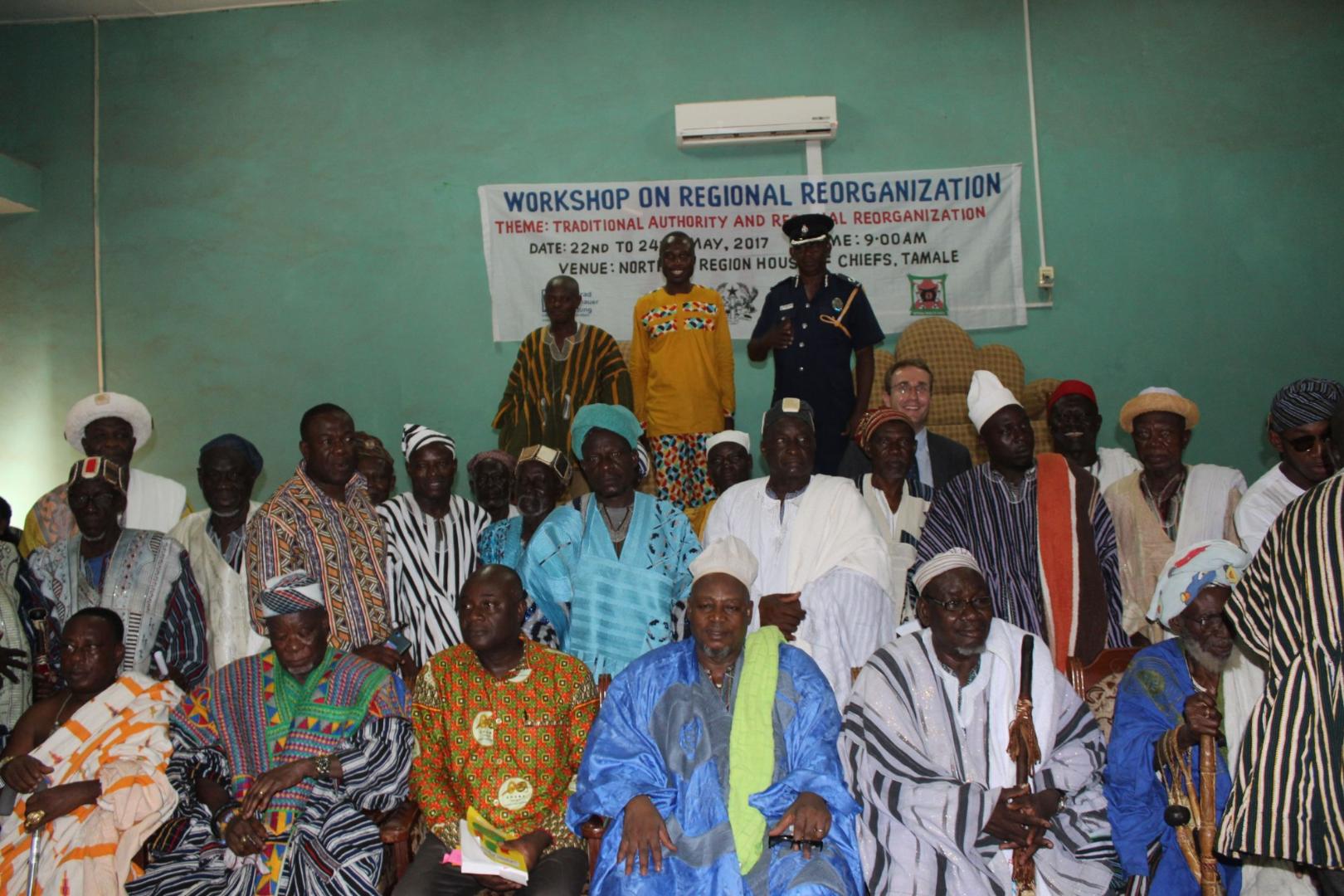Group photo of participants at a workshop on regional reorganization in Tamale. The men, most wearing traditional attire, pose together in front of an event banner.