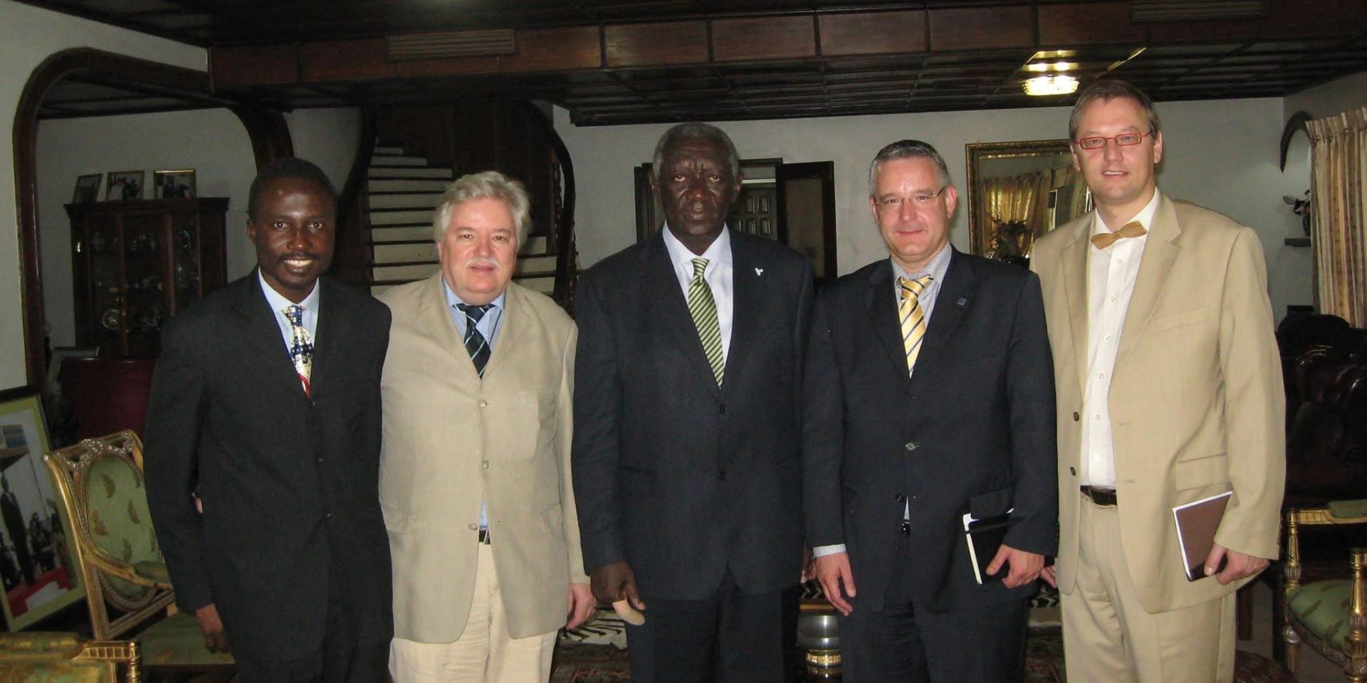 Group photo of five men in suits at a meeting between German and Ghanaian representatives indoors.