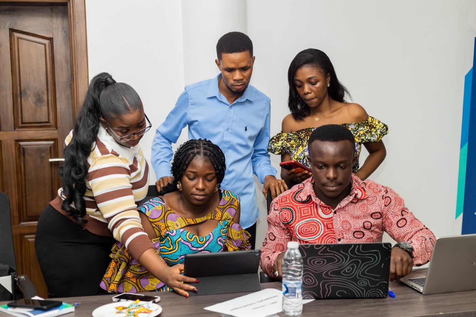 Five young adults work together on laptops and a tablet during an orientation workshop for Konrad Adenauer Stiftung scholarship holders in Ghana.