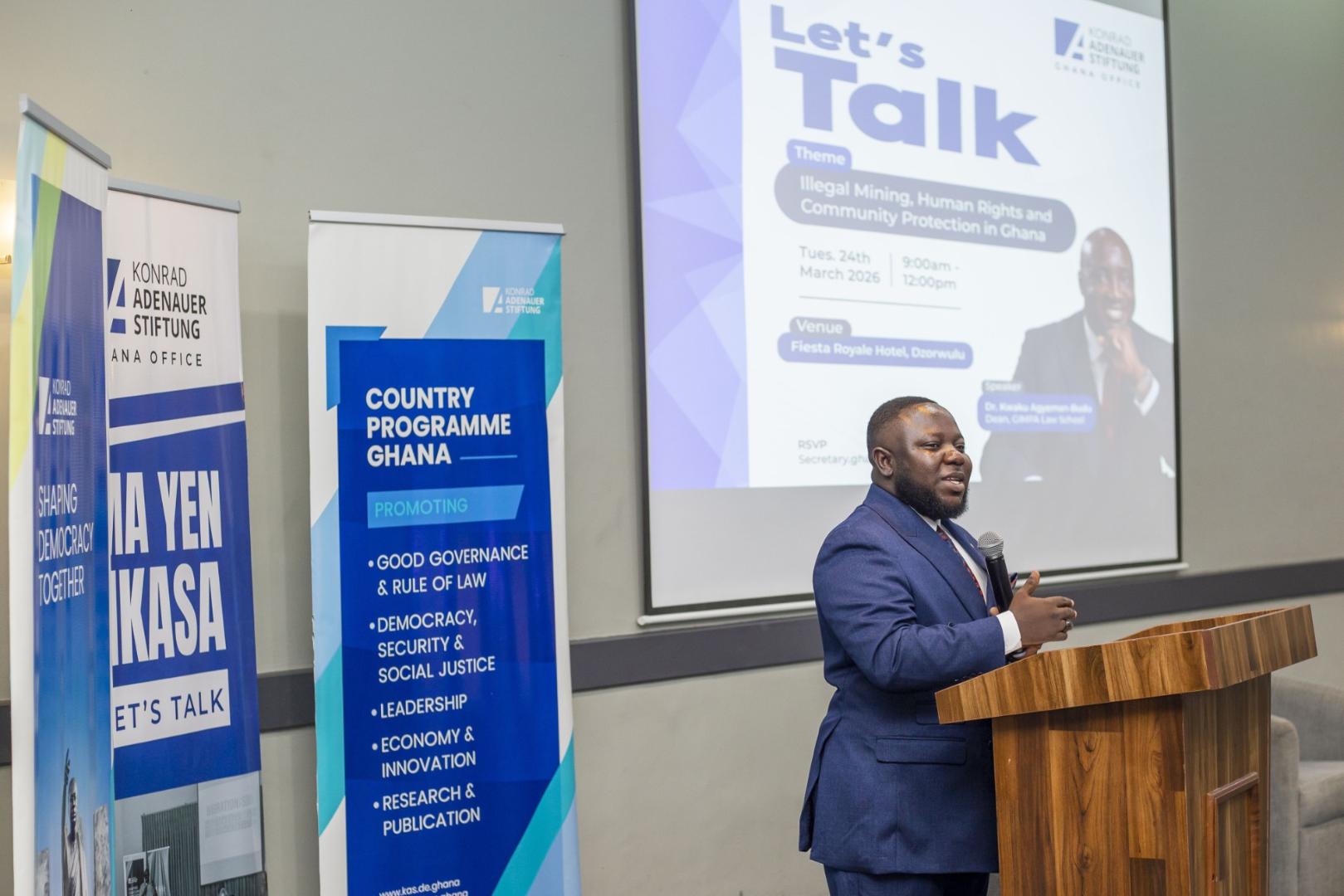 A man in a blue suit speaks at a podium during the Konrad Adenauer Stiftung's 